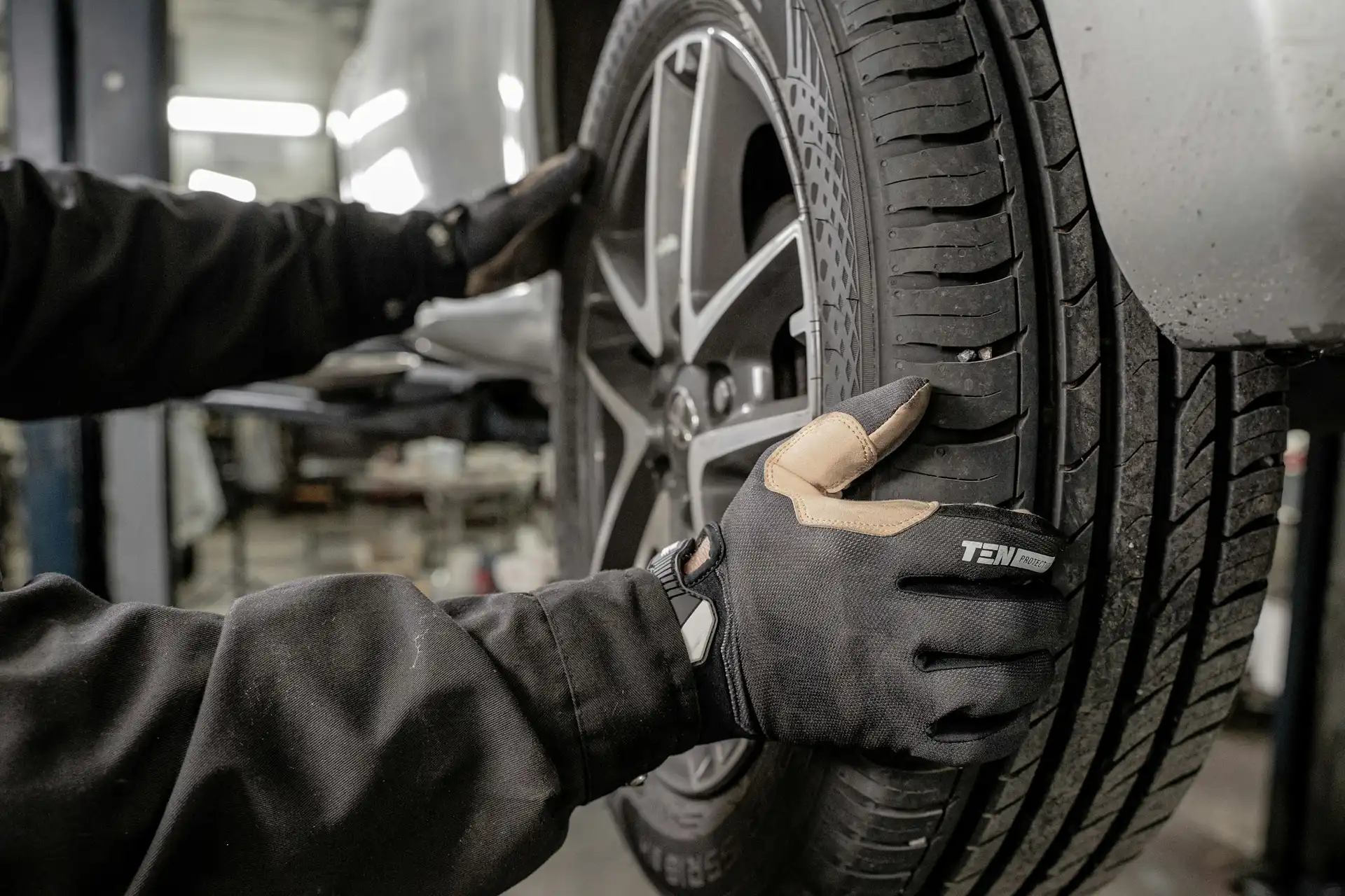 A technician fitting a tyre in a workshop bay